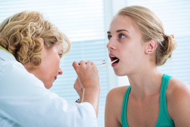 A doctor examines a tonsil. 